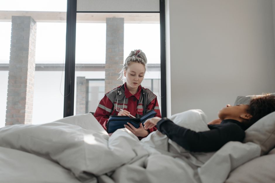 Healthcare worker taking notes while attending to patient at home